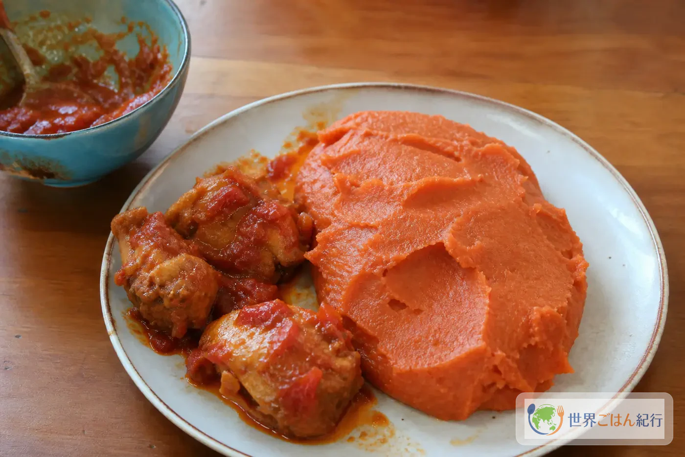ベナンのアミウォを赤いとうもろこし粉のドームにし、鶏のトマトソースを添えた皿